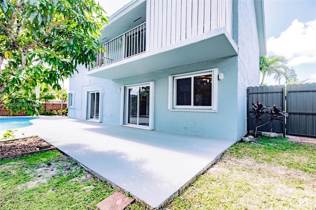 rear view of property with a balcony, a fenced in pool, and a patio area