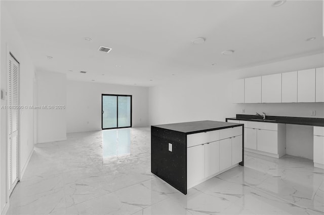 kitchen featuring white cabinetry, sink, and a kitchen island