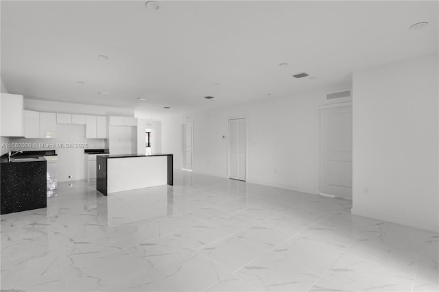 kitchen with white cabinetry, a center island, and sink