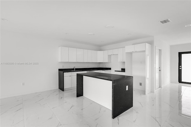 kitchen with a center island, sink, and white cabinets