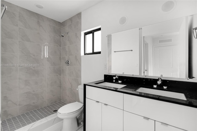 bathroom featuring tiled shower, vanity, and toilet