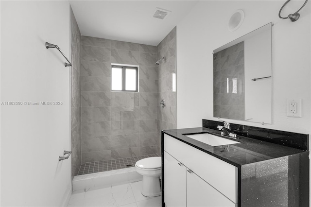 bathroom featuring vanity, tiled shower, and toilet