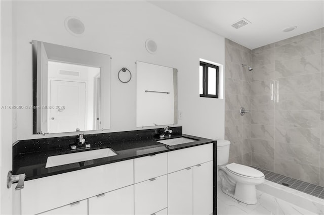 bathroom with vanity, toilet, and tiled shower