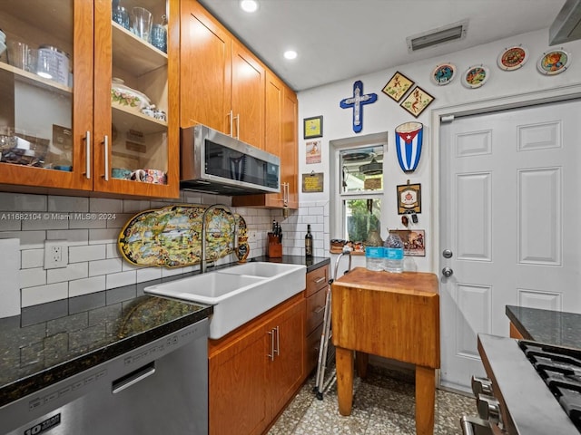 kitchen featuring appliances with stainless steel finishes, dark stone countertops, tasteful backsplash, and sink