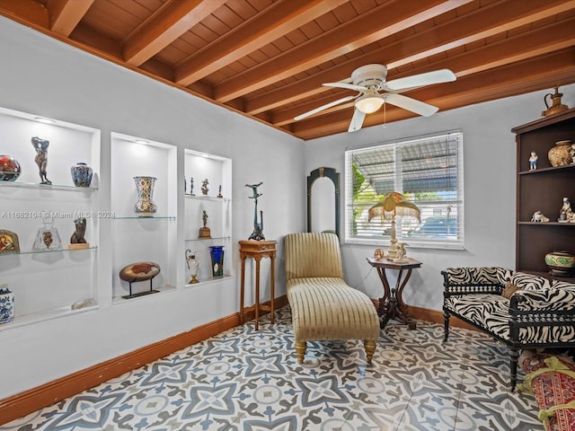 sitting room featuring ceiling fan, beamed ceiling, wooden ceiling, and built in shelves