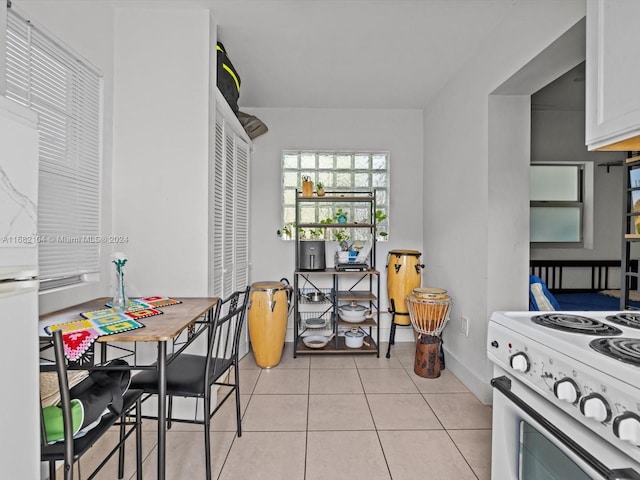 kitchen with white appliances, light tile patterned floors, and white cabinets