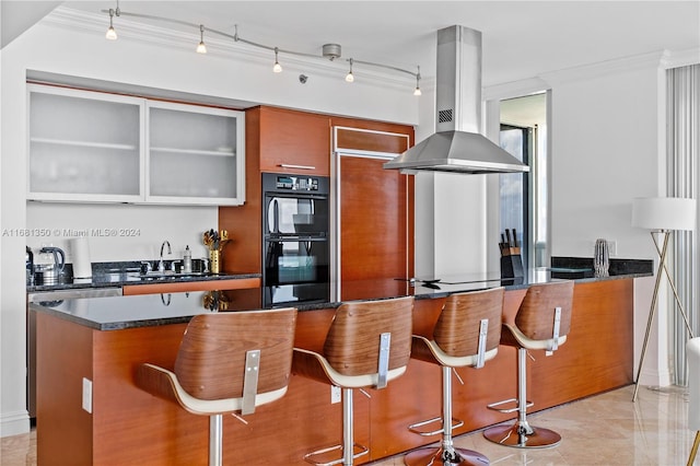 kitchen with sink, island range hood, crown molding, a breakfast bar, and black double oven