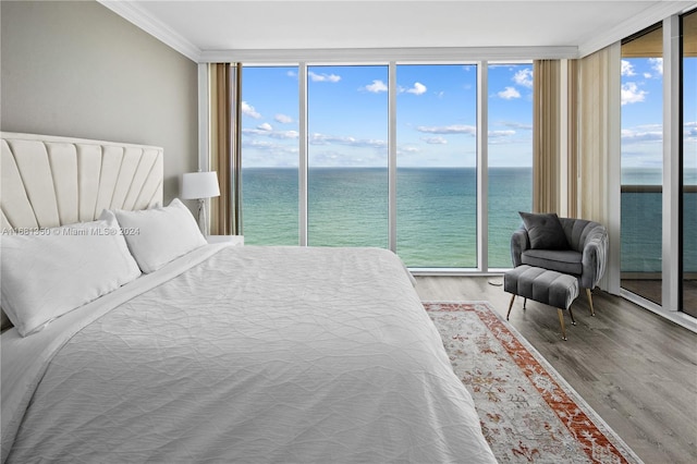 bedroom featuring floor to ceiling windows, hardwood / wood-style floors, access to exterior, and a water view