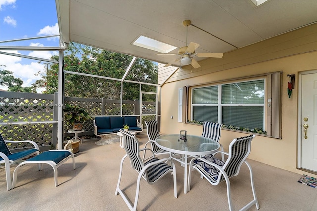 view of patio featuring ceiling fan, outdoor lounge area, and glass enclosure