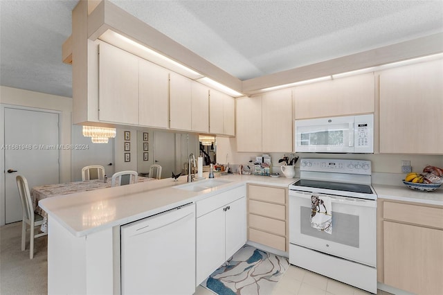 kitchen with white appliances, sink, a textured ceiling, kitchen peninsula, and an inviting chandelier