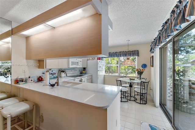 kitchen featuring kitchen peninsula, white cabinets, a breakfast bar area, sink, and white appliances