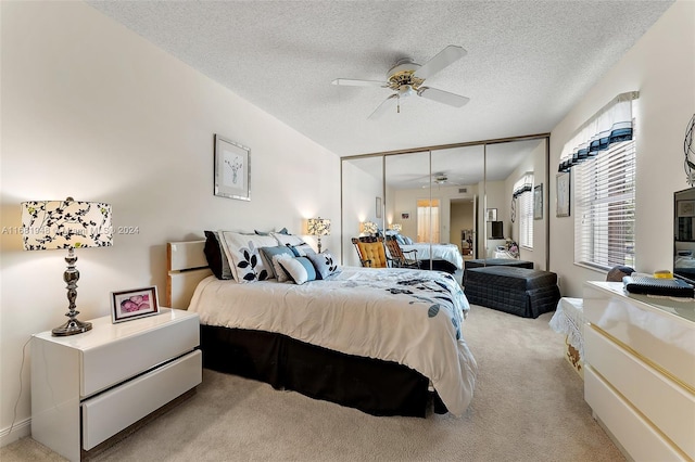 bedroom featuring a closet, ceiling fan, a textured ceiling, and light colored carpet