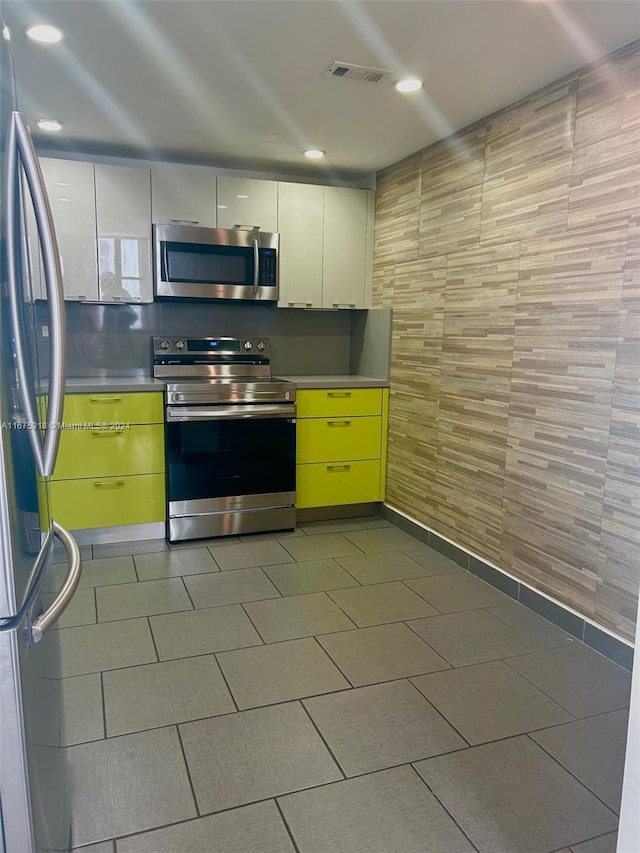 kitchen featuring appliances with stainless steel finishes, white cabinetry, and tile walls