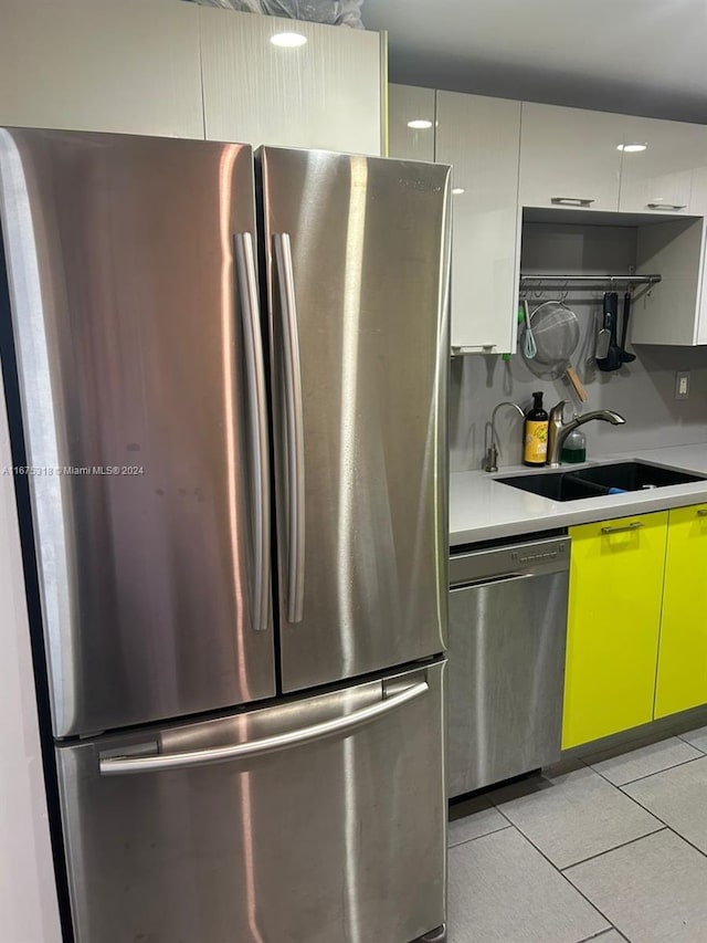 kitchen with light tile patterned flooring, sink, white cabinetry, and stainless steel appliances