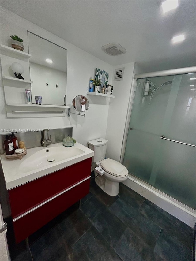 bathroom featuring tile patterned flooring, vanity, toilet, and a shower with door