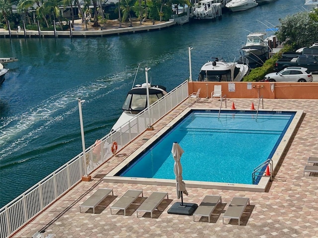 view of swimming pool with a patio area and a water view