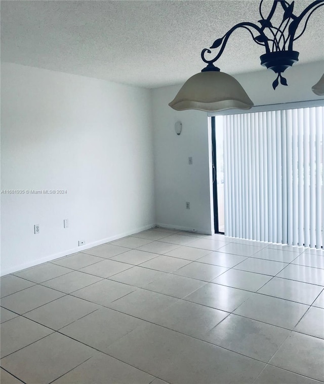 spare room with a textured ceiling and light tile patterned floors