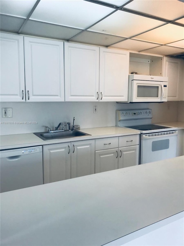 kitchen with white appliances, sink, and white cabinets