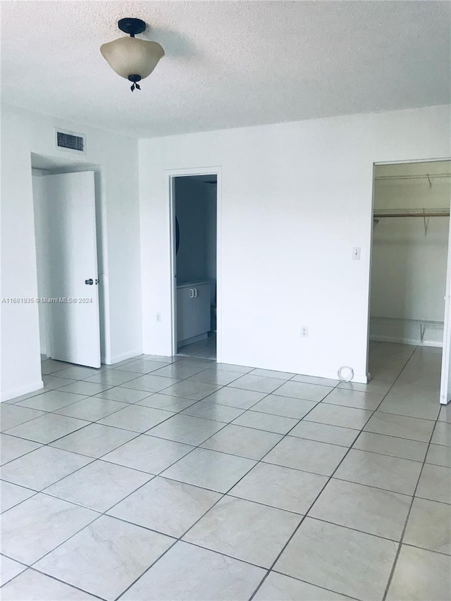 empty room with a textured ceiling and light tile patterned floors