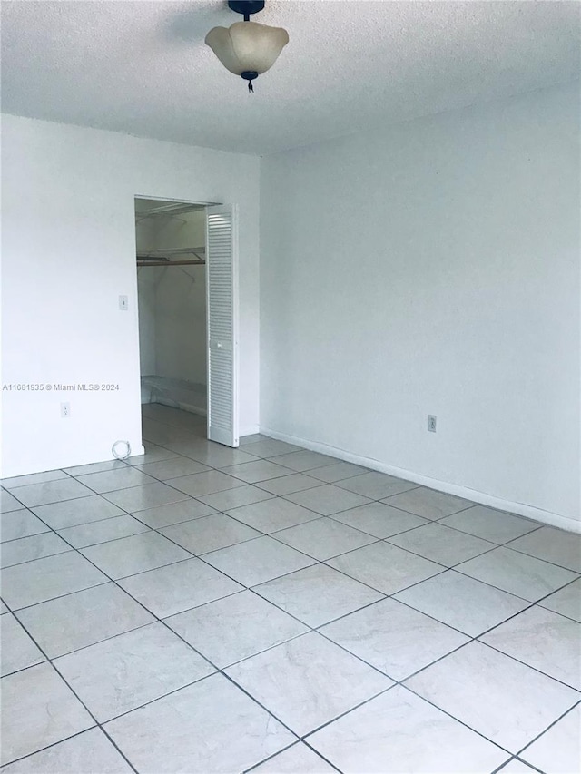 unfurnished room featuring a textured ceiling and light tile patterned floors