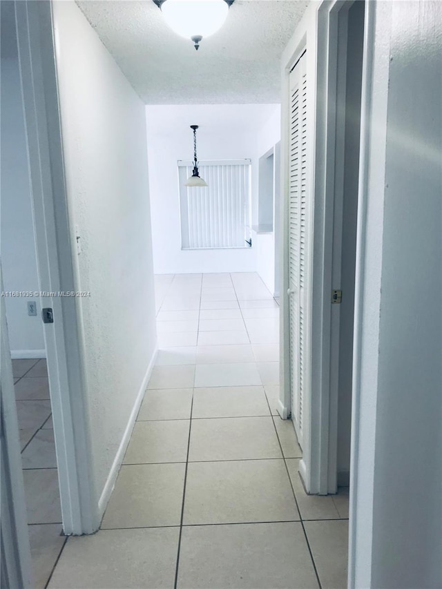 corridor with a textured ceiling and light tile patterned flooring