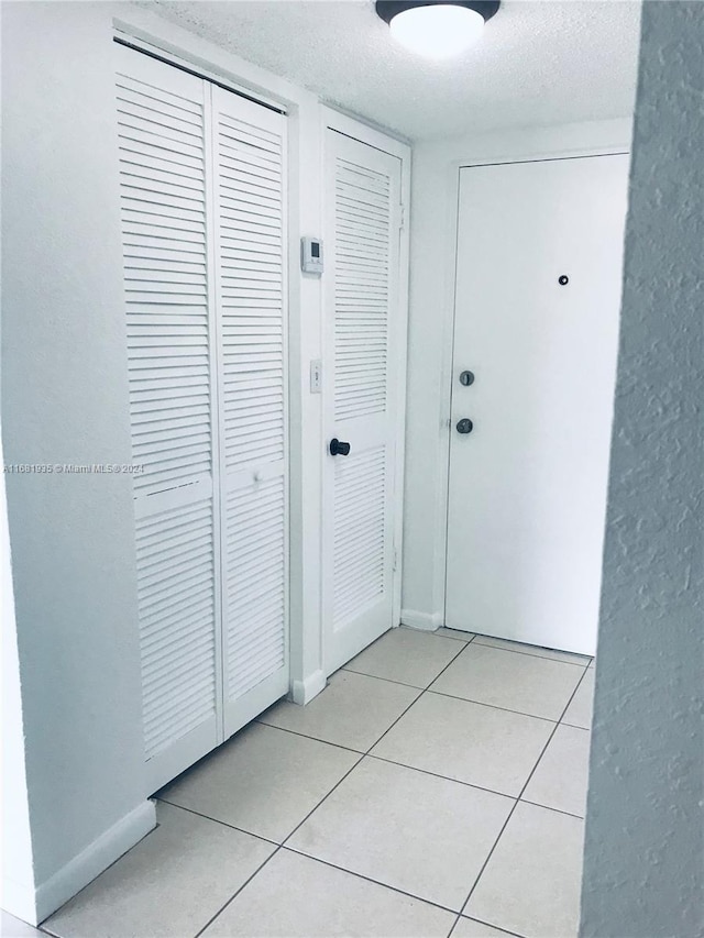 corridor featuring a textured ceiling and light tile patterned flooring