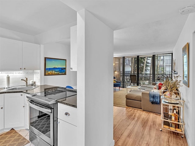 kitchen featuring decorative backsplash, stainless steel range with electric cooktop, white cabinetry, light hardwood / wood-style flooring, and sink