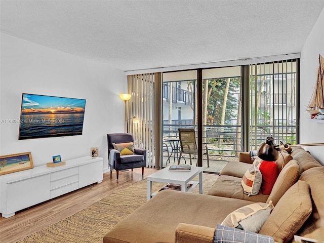 living room with hardwood / wood-style flooring, a textured ceiling, and a wall of windows