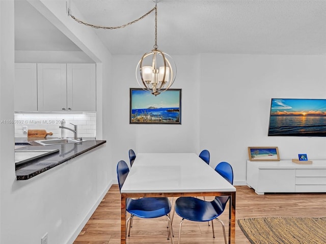 dining space with a chandelier, sink, and light wood-type flooring