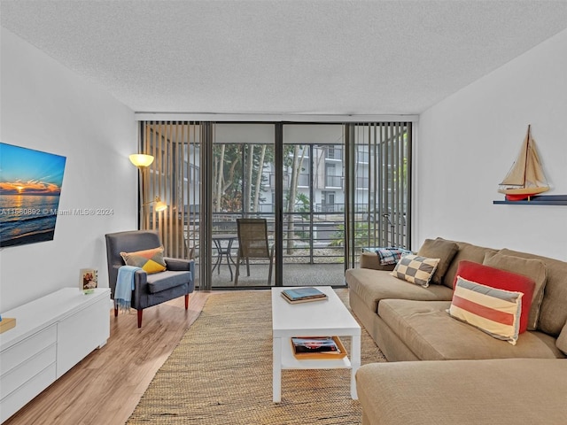 living room with expansive windows, a textured ceiling, and light wood-type flooring