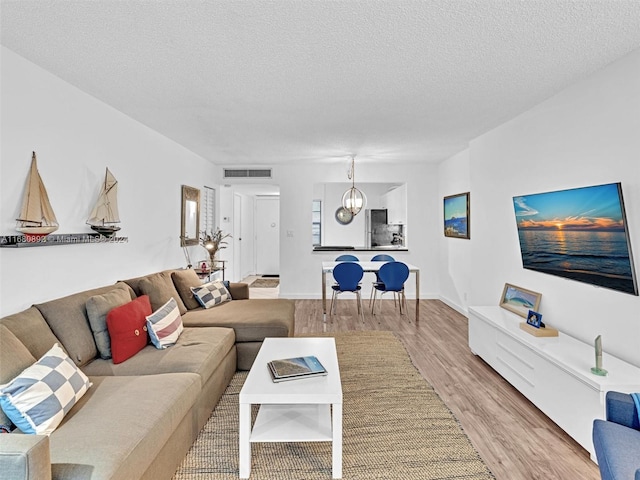 living room with a textured ceiling and light wood-type flooring