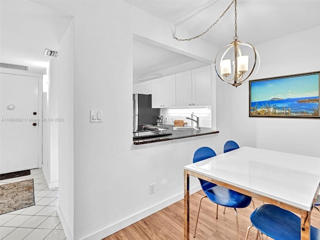 dining space with light hardwood / wood-style floors, an inviting chandelier, a textured ceiling, and sink