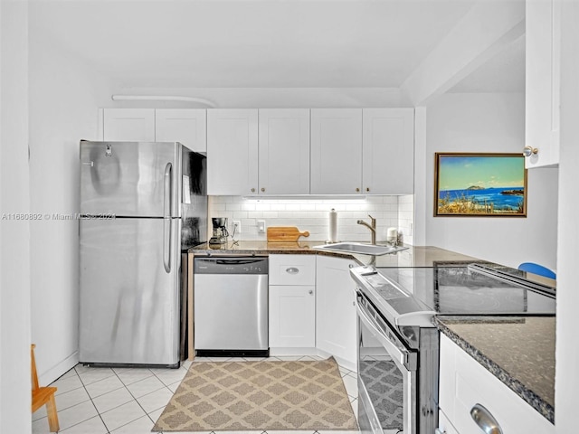 kitchen featuring decorative backsplash, dark stone countertops, sink, white cabinets, and appliances with stainless steel finishes