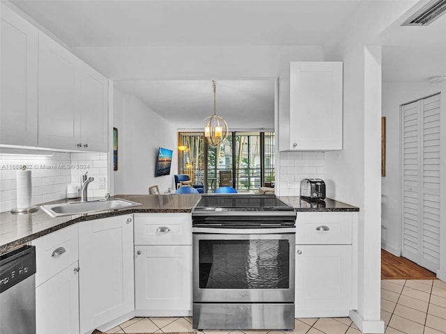 kitchen with appliances with stainless steel finishes, sink, white cabinetry, light tile patterned floors, and a chandelier