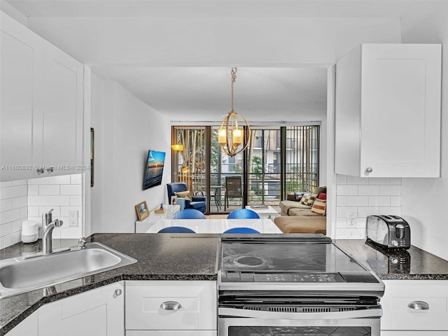 kitchen featuring backsplash, stainless steel stove, sink, a chandelier, and white cabinets