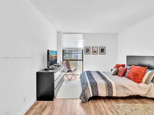 bedroom featuring expansive windows, a textured ceiling, and light wood-type flooring