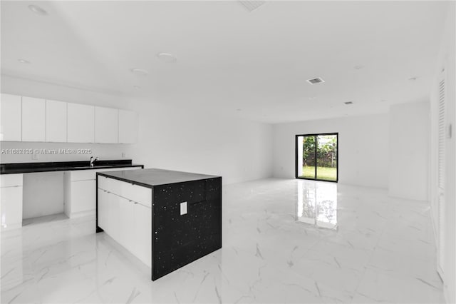 kitchen featuring a center island, sink, and white cabinets