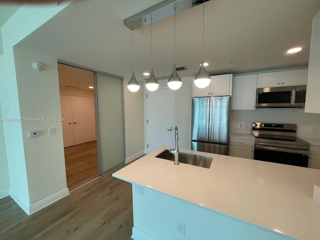 kitchen with sink, light hardwood / wood-style floors, stainless steel appliances, pendant lighting, and white cabinets