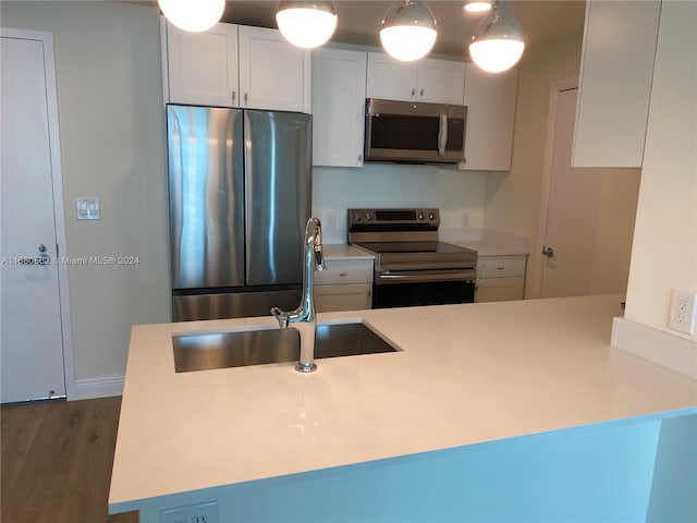 kitchen with appliances with stainless steel finishes, sink, dark hardwood / wood-style flooring, white cabinetry, and decorative light fixtures