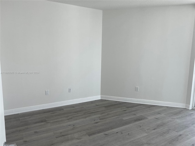 unfurnished room with dark wood-type flooring