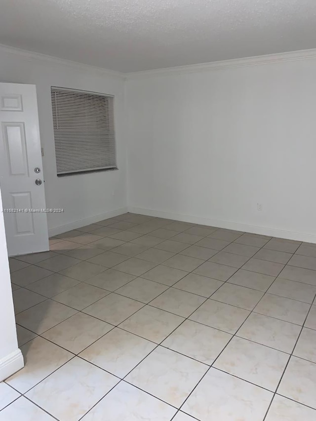 tiled spare room with crown molding and a textured ceiling