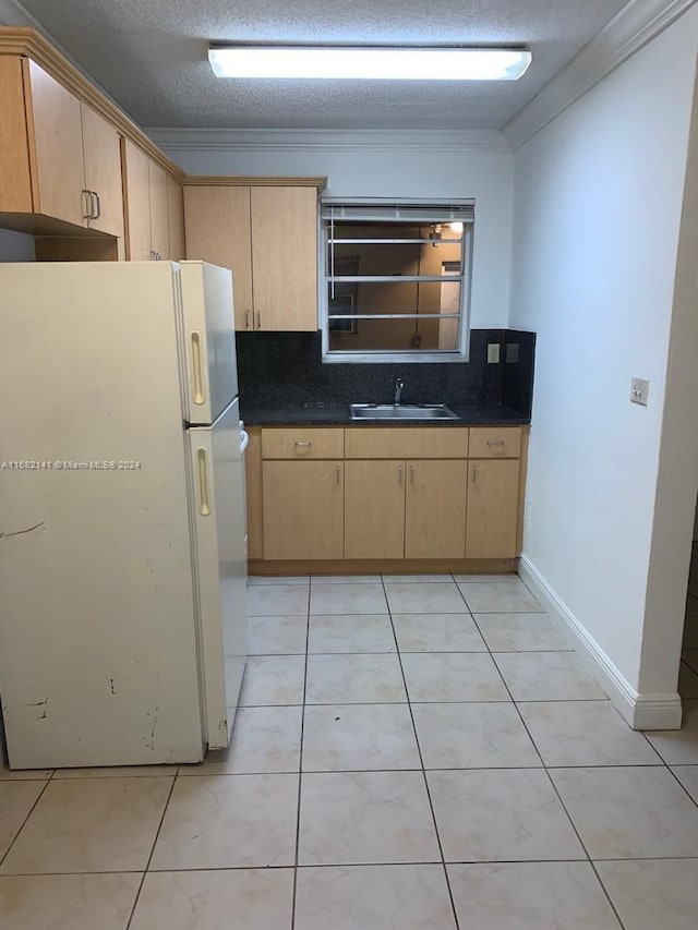 kitchen with ornamental molding, light brown cabinets, white fridge, and a textured ceiling