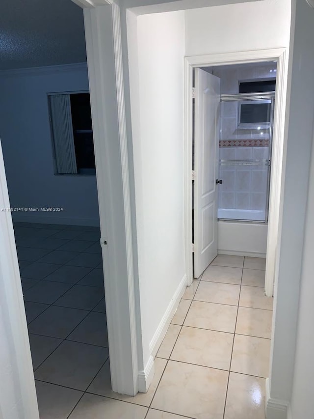 corridor with crown molding and light tile patterned floors