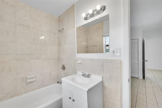 bathroom with tile patterned floors, vanity, tile walls, and tiled shower / bath