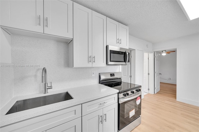 kitchen featuring sink, ceiling fan, a textured ceiling, appliances with stainless steel finishes, and white cabinetry