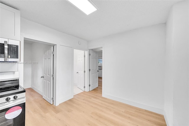 kitchen with white cabinets, range, a textured ceiling, and light hardwood / wood-style flooring