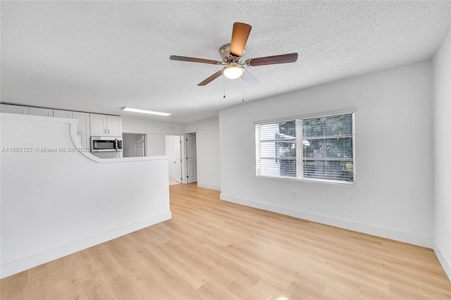 unfurnished living room with ceiling fan, light hardwood / wood-style floors, and a textured ceiling