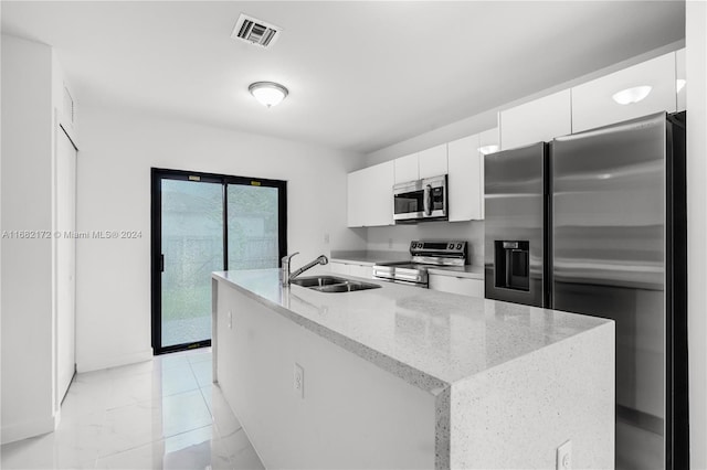 kitchen with appliances with stainless steel finishes, white cabinetry, sink, and light stone counters