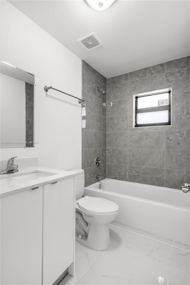 full bathroom with tiled shower / bath, vanity, and toilet