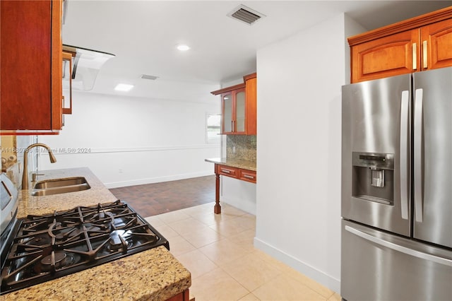 kitchen with decorative backsplash, light stone counters, stainless steel fridge with ice dispenser, light tile patterned flooring, and sink